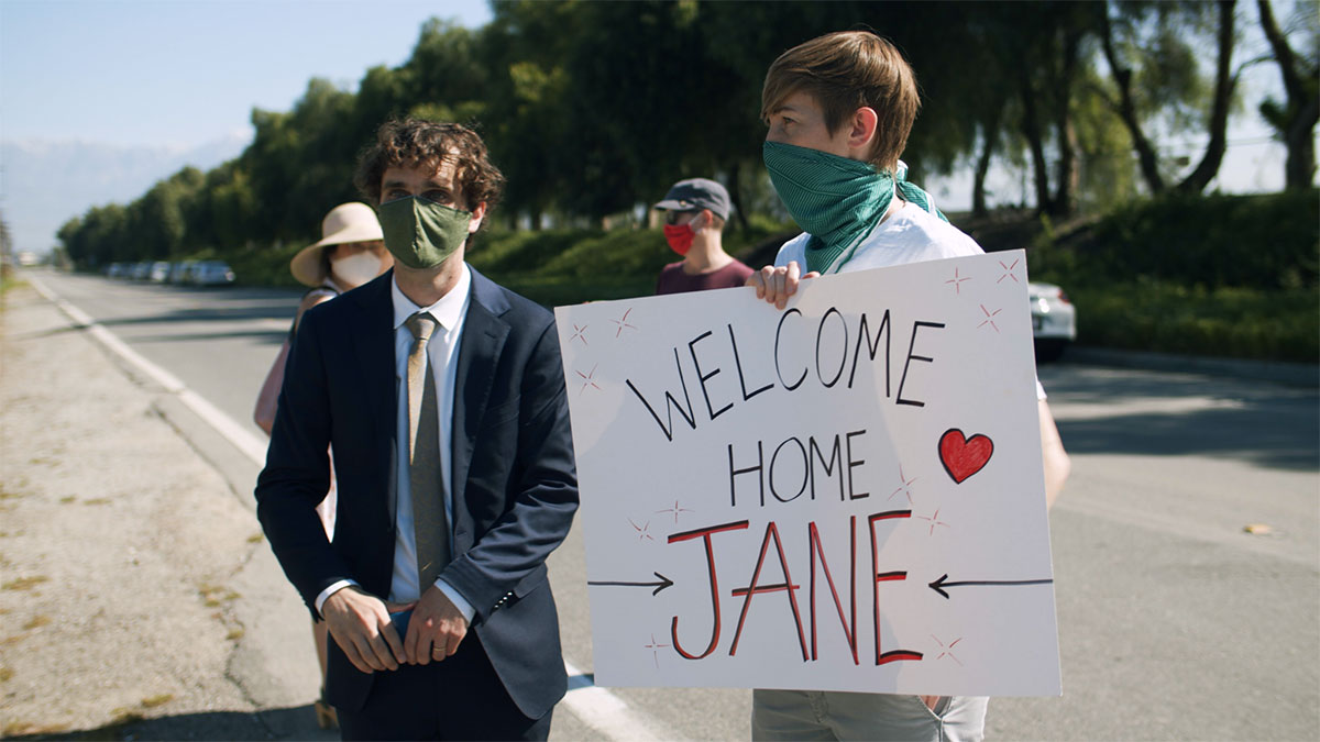Two students holding a sign saying Welcome Home Jane