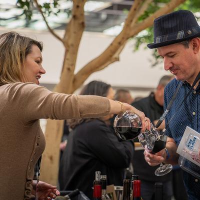 A glass of wine is poured into an LMU Wine Classic wine glass as a guest smiles.