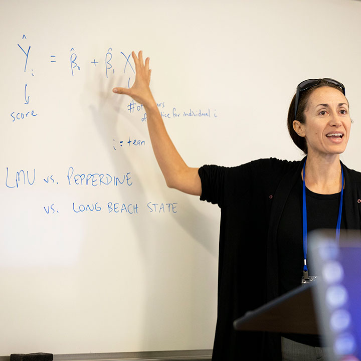 A lecturer pointing to information on a white board