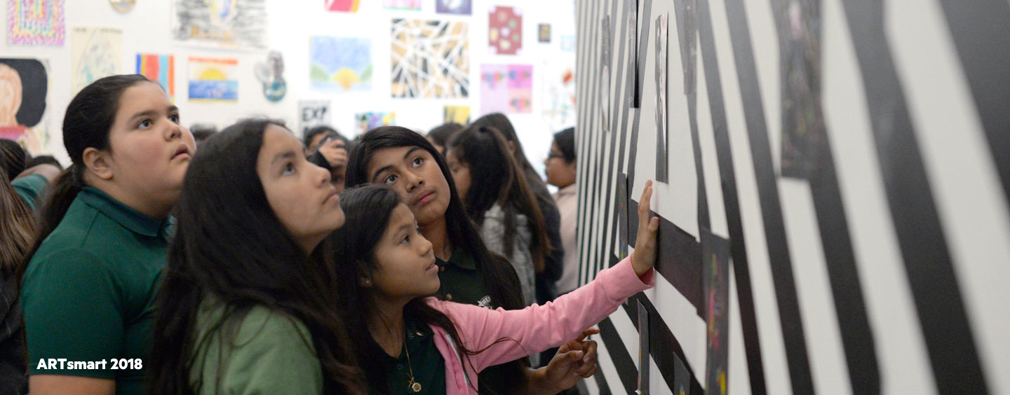 Middle school students observing a hung art piece during ARTsmart 2018