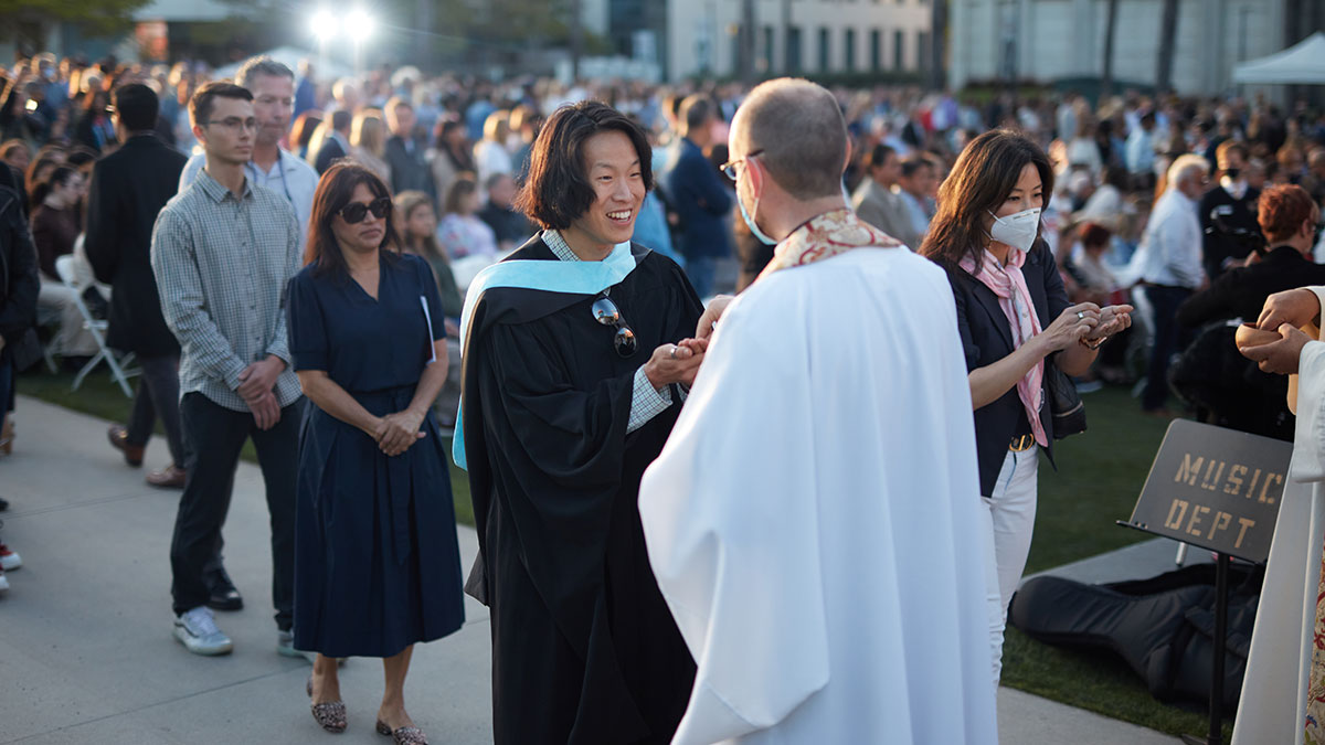 People approaching priests during Commencement Mass at the Drollinger Family Stage