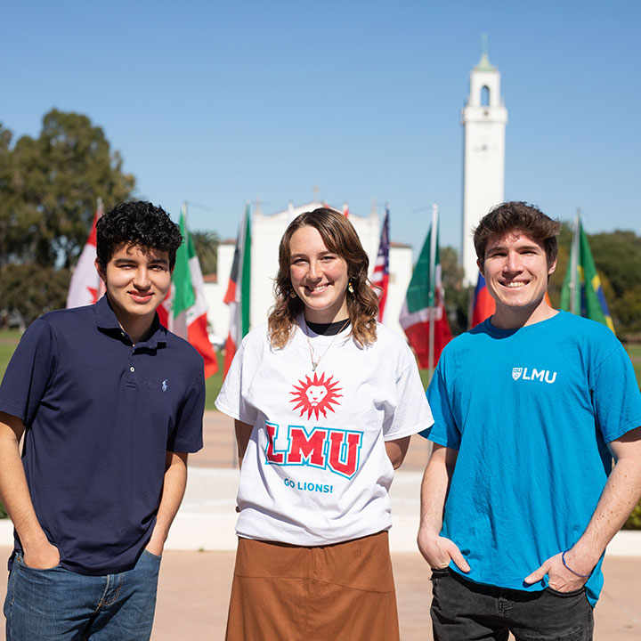 Students smiling while standing in Regents Terrance with Sacred Heart Chapel in the background