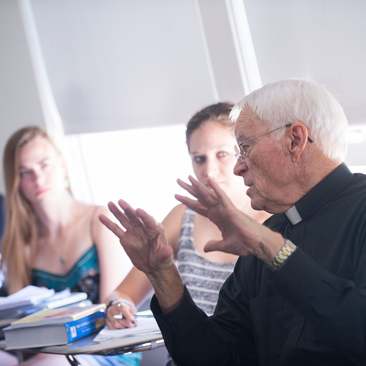 A priest speaking to students in a classroom