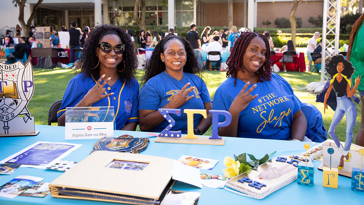 Three representatives for Sigma Gamma Rho at a booth during an event