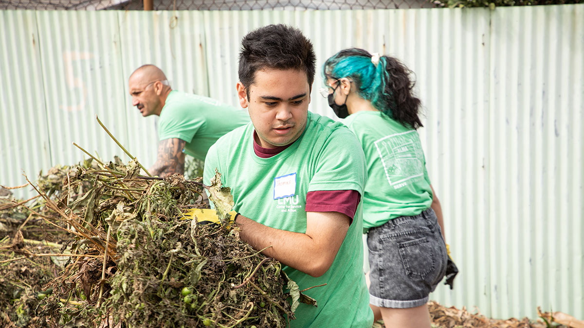 Three students cleaning up plant waste wearing Center for Service and Action shirts