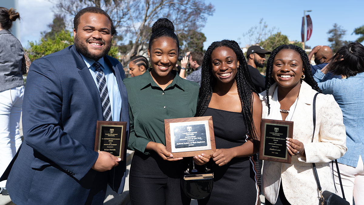 Four students holding award plaques at an event in Sunken Garden