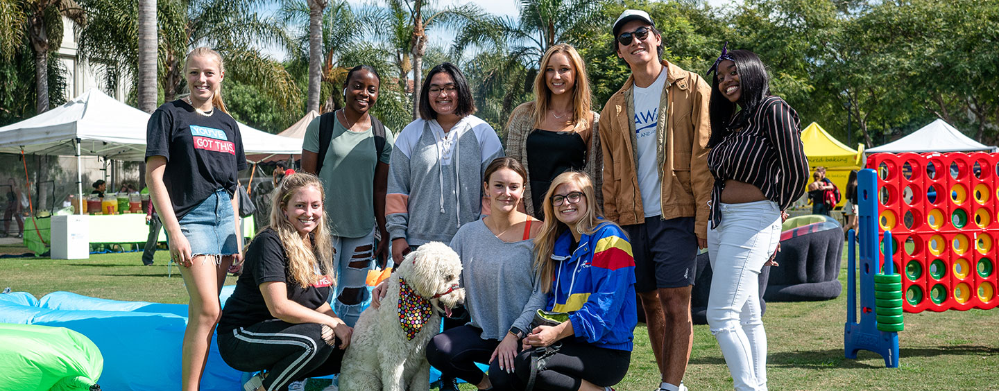 Students standing together in Lawton Plaza with Buster the therapy dog