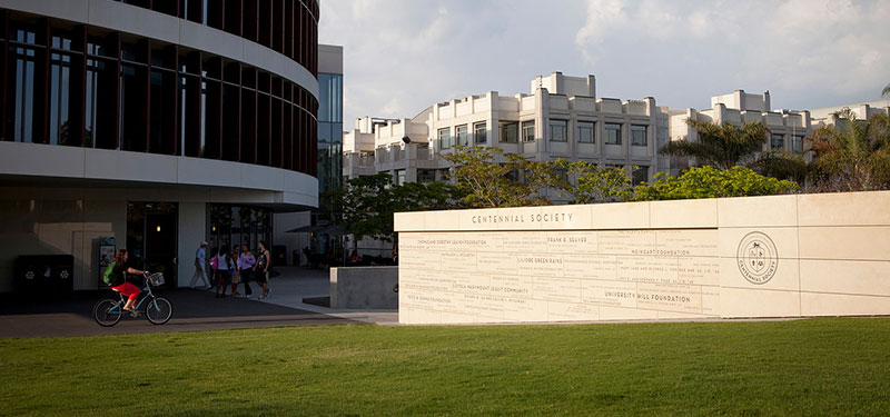 Centennial Society monument outside of the William H. Hannon Library with students passing by