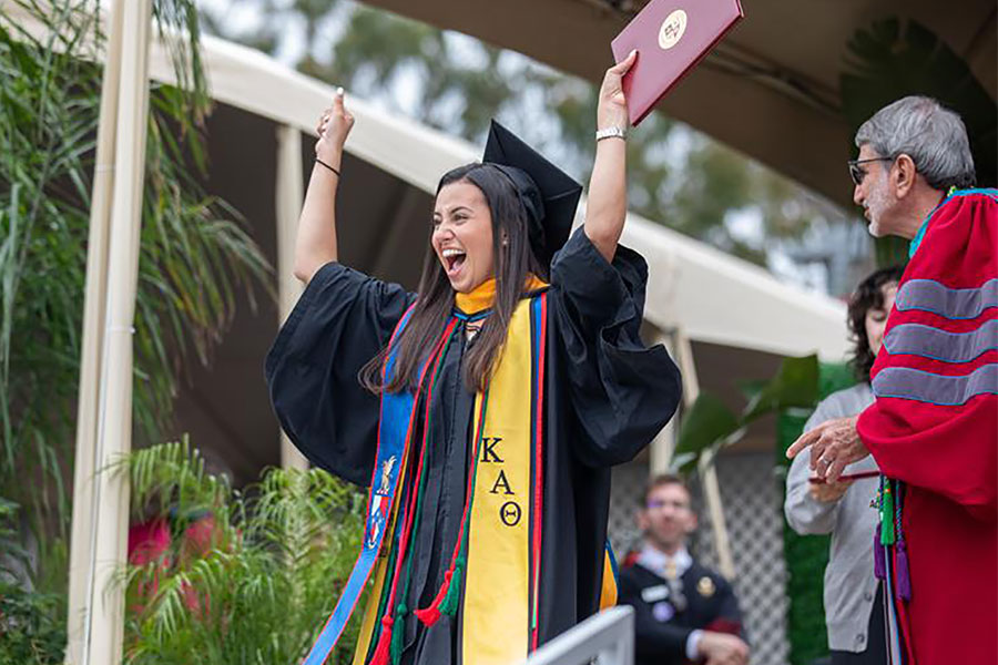 A new graduate celebrates after receiving her diploma at LMU's Commencement.