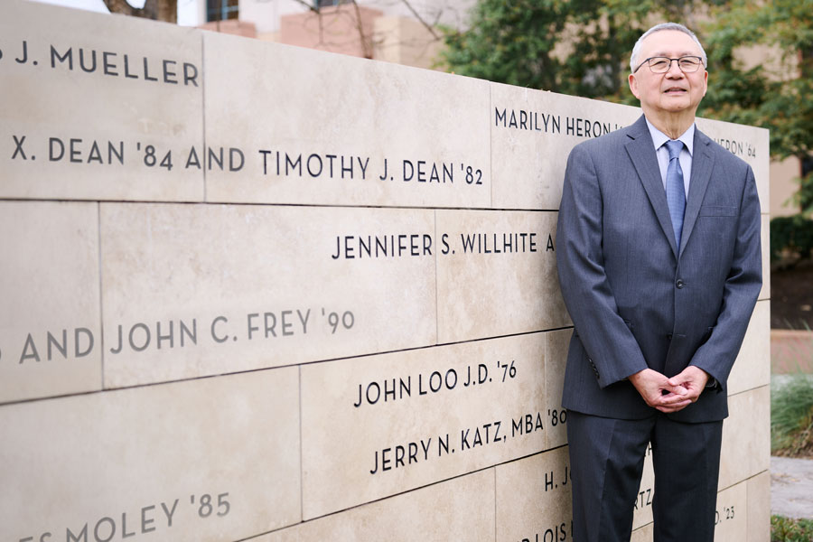 John Loo, J.D. '76, stands by his name on the Centennial Wall for donors of $1 million or greater to the university.